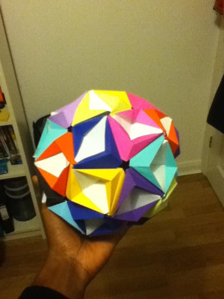 A multicoloured modular origami ball held in one hand